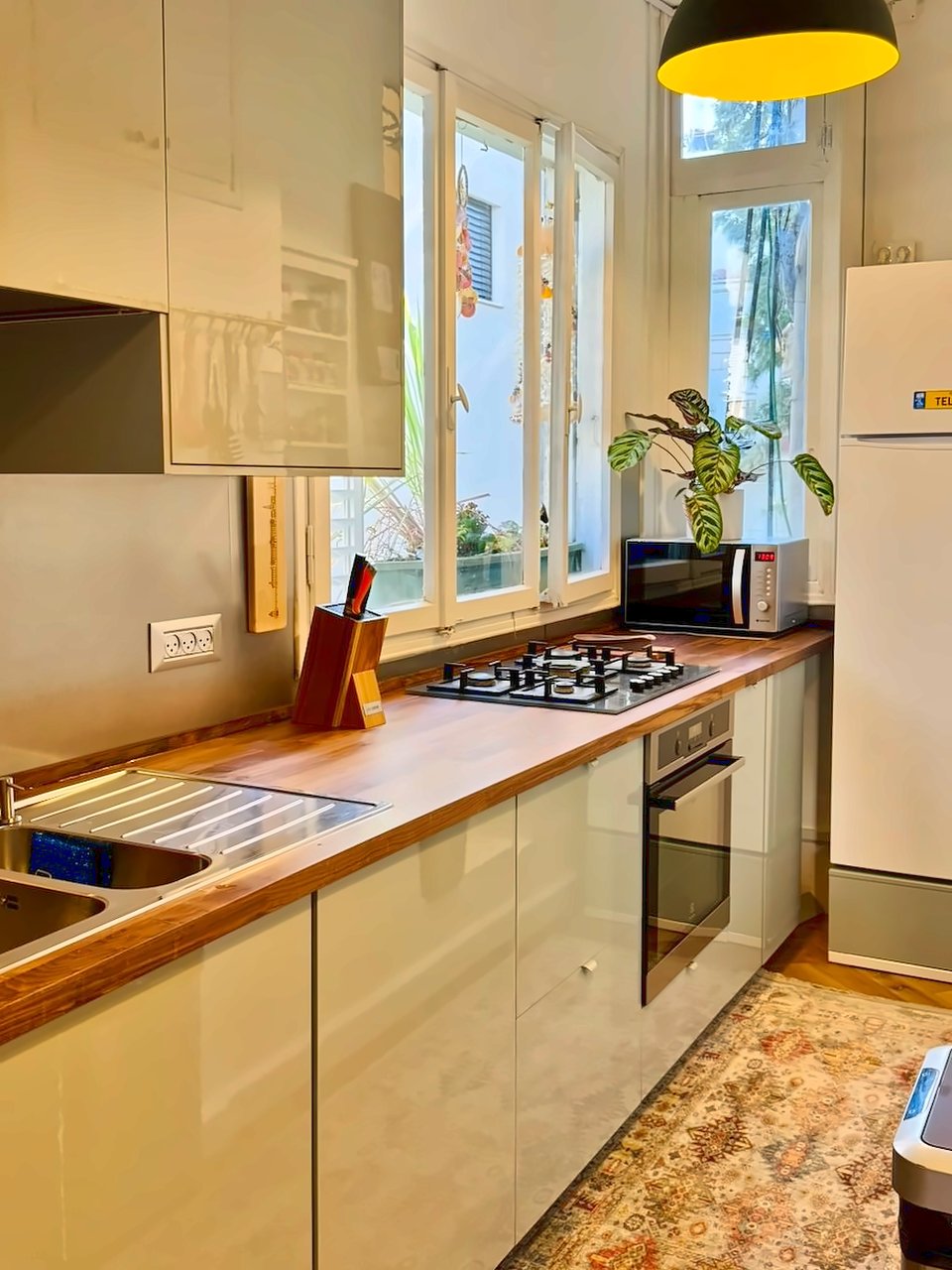 La cuisine : plans de travail en bois, plaques de cuisson et fenêtre